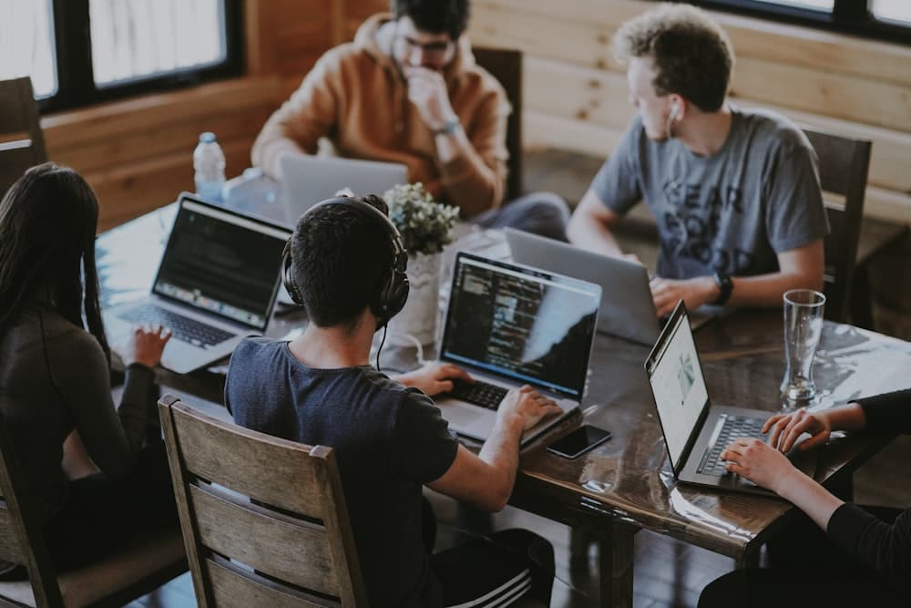 Tim developer startup bekerja bersama di laptop